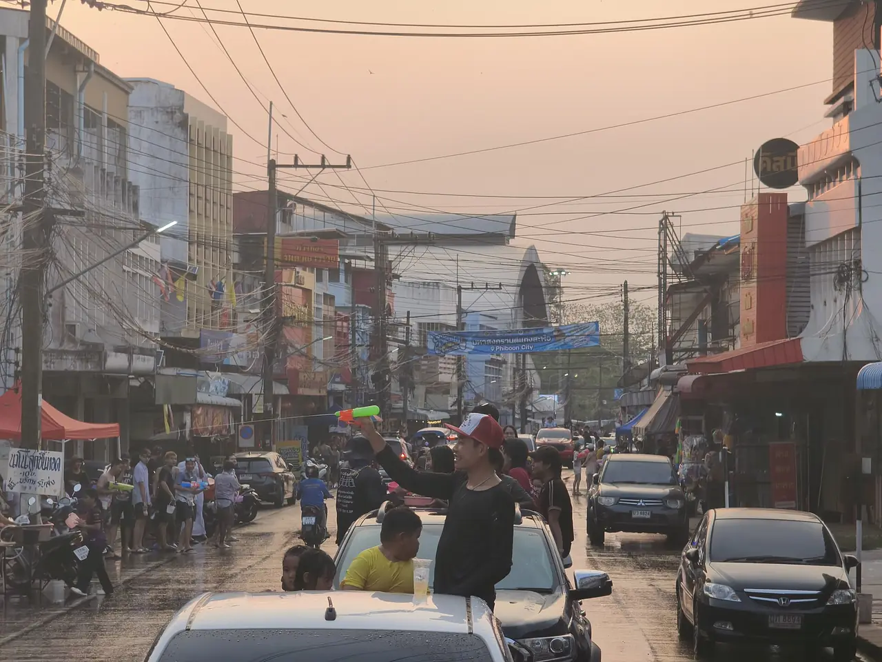 ถนนในเมืองพิบูลมังสาหารช่วงสงกรานต์ มีคนบนรถกระบะถือปืนฉีดน้ำ ภาพจาก Wikimedia Commons ผู้ถ่าย PhiPhiUbon สัญญา CC0 ภาพวันที่ 13 เม.ย. 2569 เป็นภาพบรรยากาศในเมือง ไม่ใช่ที่แก่งสะพือโดยตรง