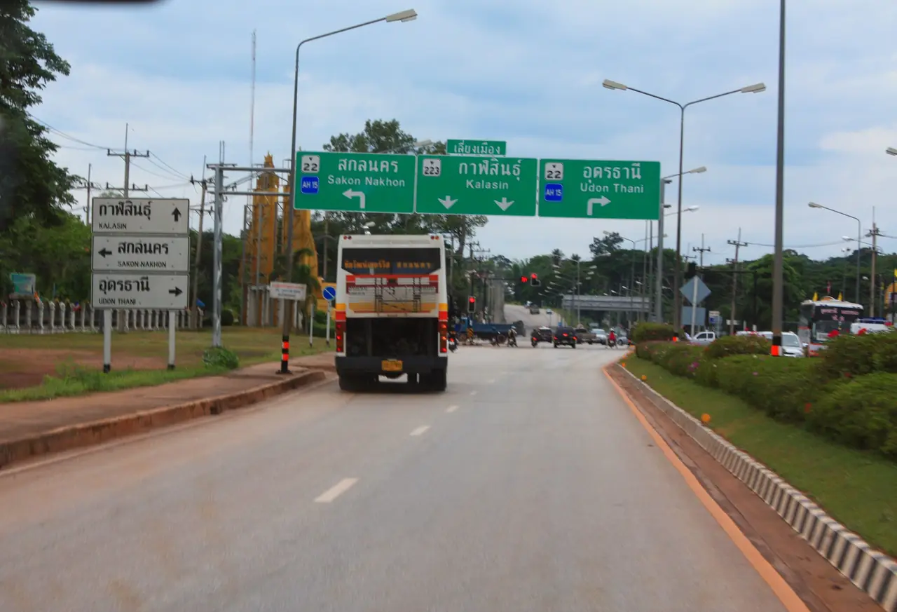 ป้ายบอกทางแยกทางหลวงหมายเลข 22 สายอุดรธานี-นครพนม กับทางหลวงหมายเลข 223 สายสกลนคร-กาฬสินธุ์ มีรถประจำทางวิ่งอยู่ ภาพจาก Wikimedia Commons ผู้ถ่าย Hdamm สัญญา CC BY 3.0 ภาพวันที่ 14 พ.ค. 2552 เป็นภาพประกอบถนนในพื้นที่ ไม่ใช่ทางเข้าวัด
