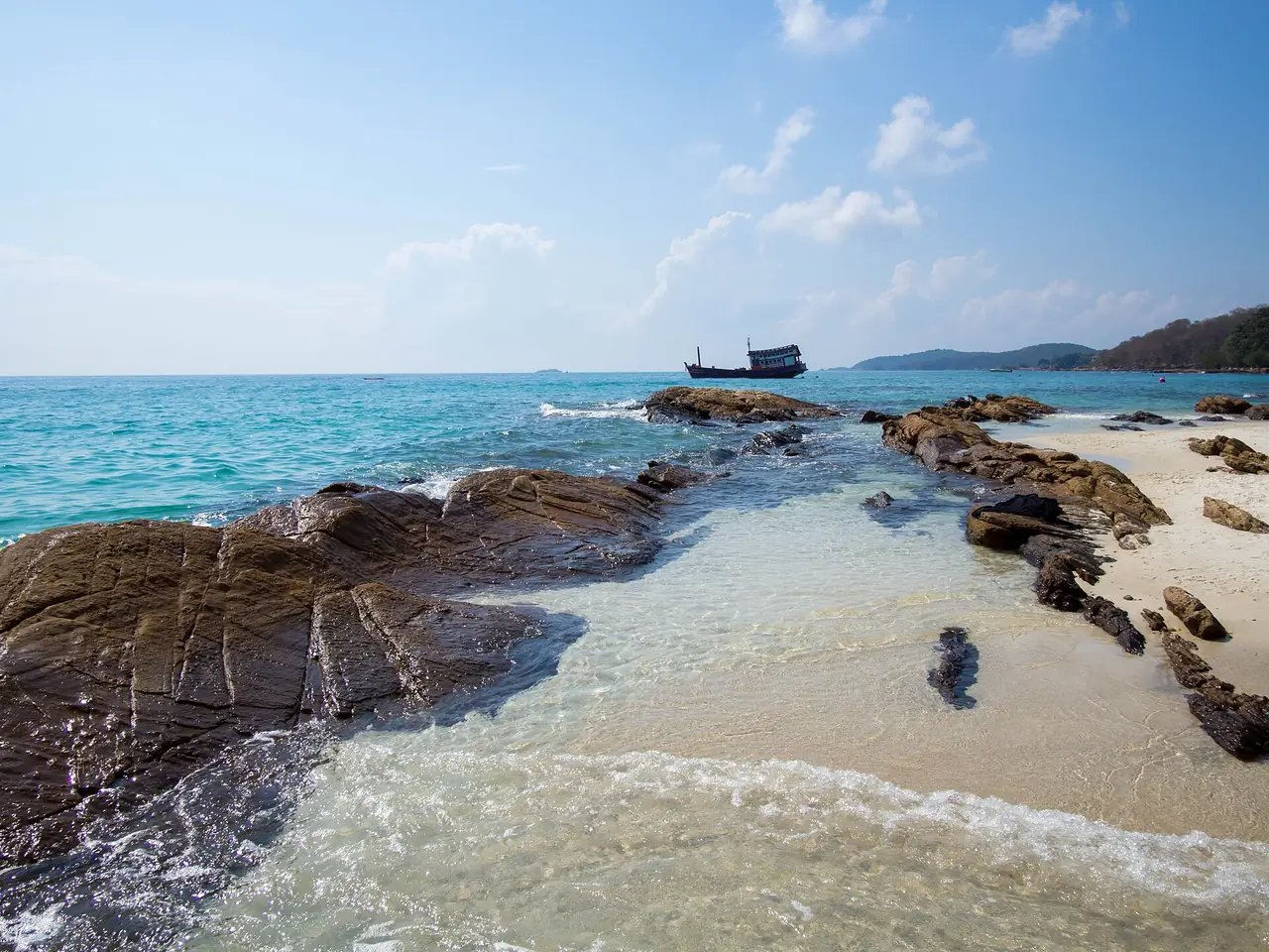 โขดหินและน้ำตื้นใสริมหาดบนเกาะเสม็ด มีเรือลำเล็กไกลออกไป ภาพถ่ายจาก Wikimedia Commons ผู้ถ่าย kishjar สัญญา CC BY 2.0 เป็นภาพประกอบ ไม่ระบุอ่าวและวัน