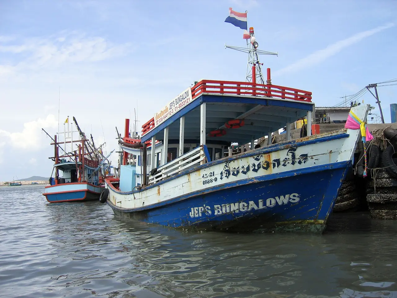 เรือโดยสารไม้สองชั้นที่ท่าเรือบ้านเพ ป้ายชื่อบนหัวเรือเป็นชื่อรีสอร์ตบนเกาะ ภาพถ่ายจาก Wikimedia Commons ผู้ถ่าย Bjørn Erik Pedersen สัญญา CC BY-SA 3.0 เป็นภาพประกอบ ลำเรือและป้ายวันนี้อาจต่างไป