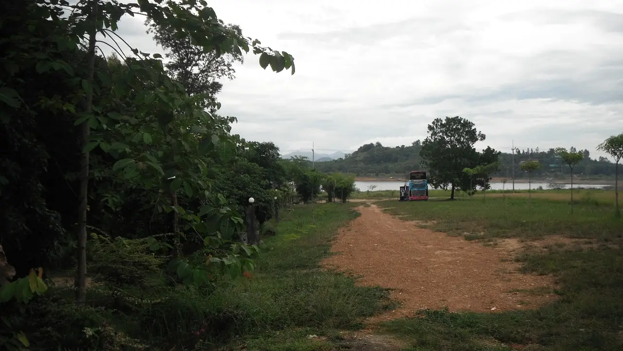 ถนนดินข้างอ่างเก็บน้ำประแสร์ในอำเภอวังจันทร์ มีรถบัสจอดไกล ๆ ภาพจาก Wikimedia Commons ผู้ถ่าย มะเดื่อ แสลงหลวง สัญญา CC BY 3.0 เป็นภาพเก่าจากชุดพาโนรามิโอ ไม่ได้ลงวันที่ ไม่ได้แสดงสภาพปัจจุบัน