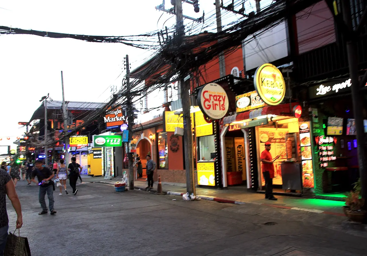 ซอยบางลาตอนเย็นแสงยังไม่หมด เห็นป้ายร้านเรียงสองฝั่งและสายไฟพาดเหนือถนน ภาพจาก Wikimedia Commons ผู้ถ่าย Karelj สัญญา สาธารณสมบัติ ถ่ายเมื่อมีนาคม 2561 เป็นภาพประกอบ ร้านและป้ายอาจเปลี่ยนไปแล้ว