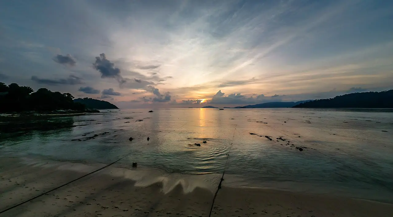 พระอาทิตย์ตกเหนือทะเลที่น้ำลง เห็นโขดและเชือกบนหาด ชื่อภาพบน Commons คือ Koh Lipe Sunset ไม่ระบุหาด เป็นภาพประกอบ ภาพถ่ายจาก Wikimedia Commons ผู้ถ่าย WIL สัญญา CC BY 2.0