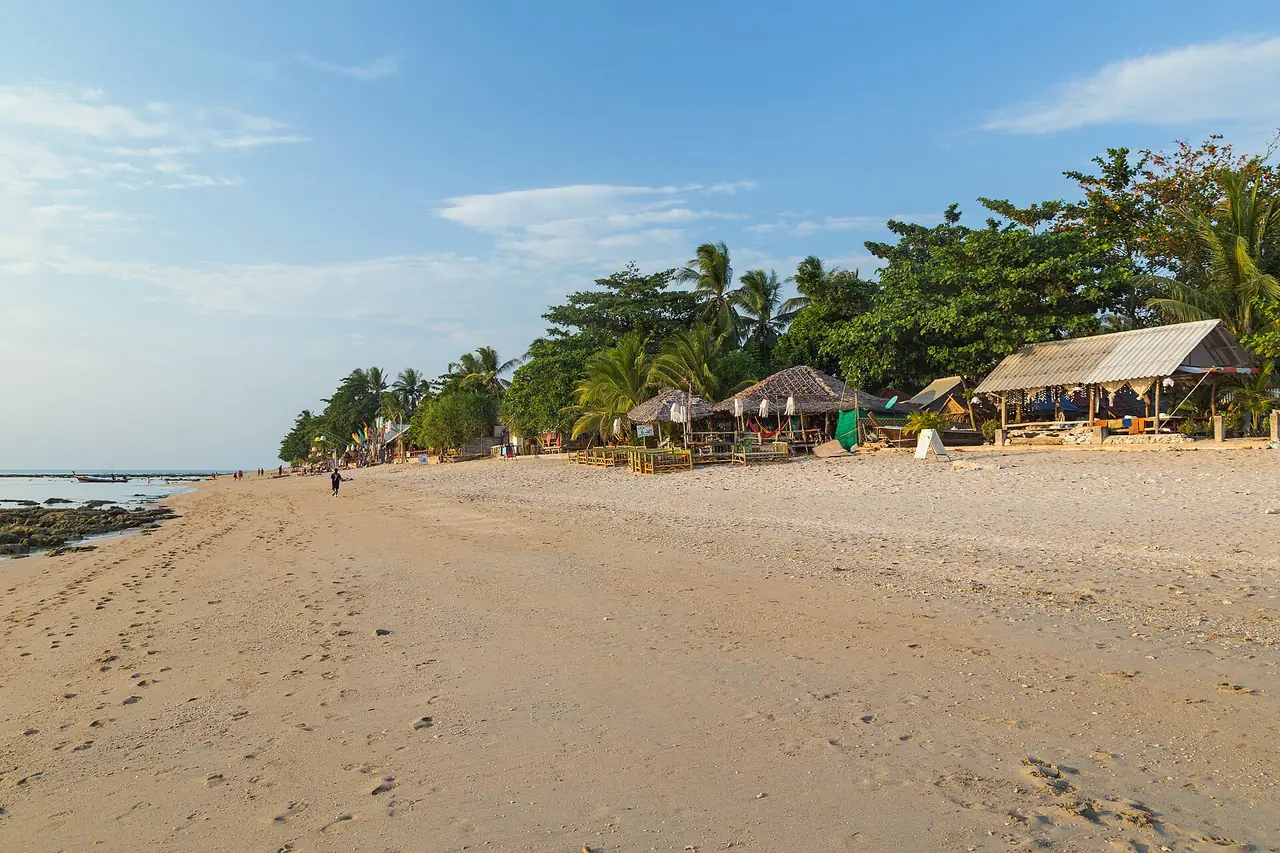 แนวหาดคลองโขงช่วงน้ำลง ร้านและกระท่อมใต้ร่มไม้ มีโขดหินโผล่ทางซ้ายของภาพ ภาพถ่ายจาก Wikimedia Commons ผู้ถ่าย Marcin Konsek ถ่ายปี 2559 สัญญา CC BY-SA 4.0