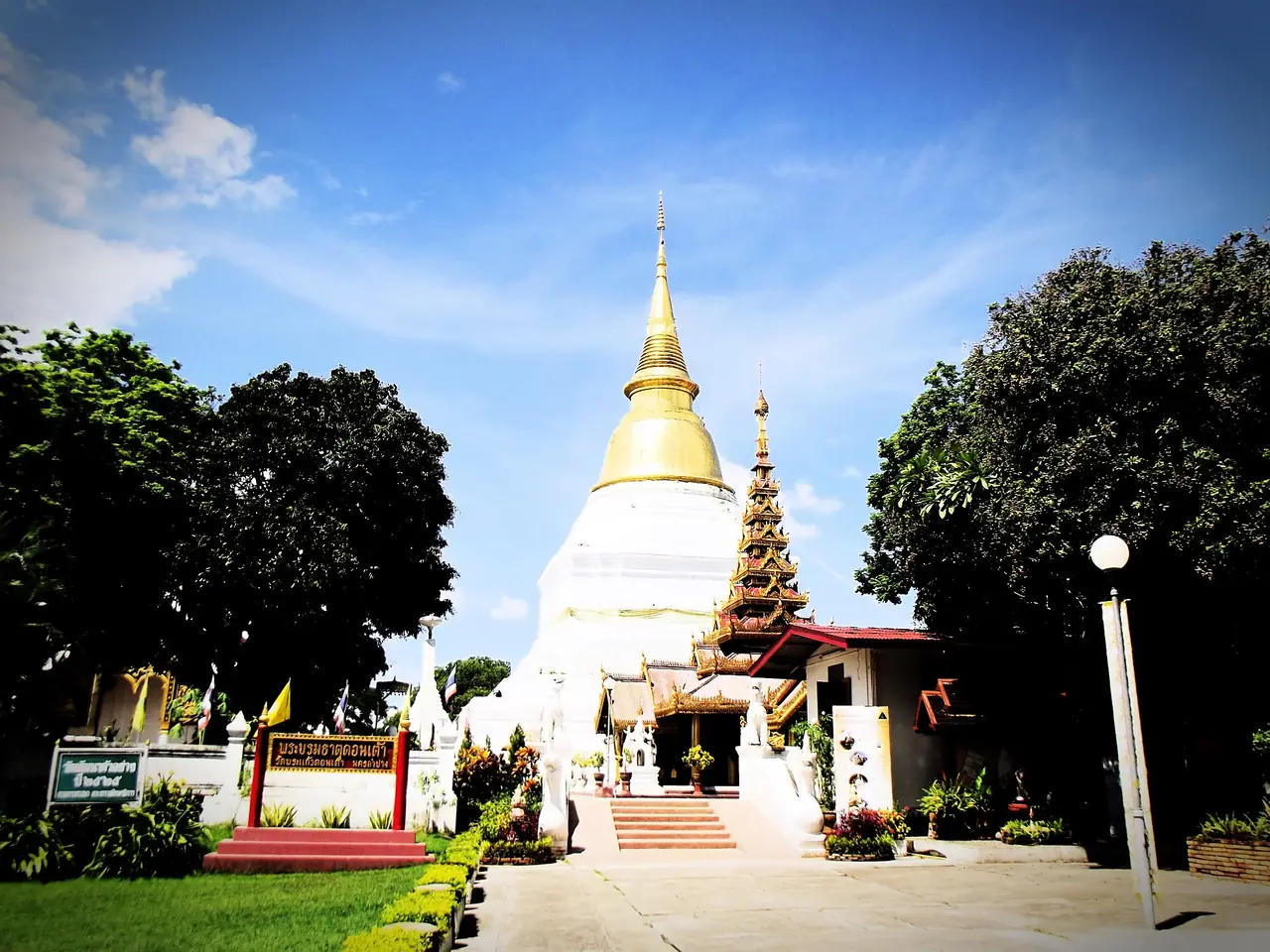 ทางเข้าวัดพระแก้วดอนเต้าสุชาดาราม เห็นพระบรมธาตุสีทองฐานสีขาวและมณฑปยอดซ้อนชั้นด้านขวา ภาพของ Angvong จาก Wikimedia Commons สัญญา CC BY-SA 3.0
