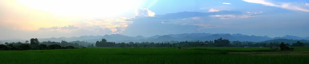 ภาพพาโนรามาของเทือกเขาทางตะวันตกเฉียงใต้ของแม่สะเรียงตอนใกล้พระอาทิตย์ตก ด้านหน้าเป็นนาข้าวสีเขียว ภาพจาก Wikimedia Commons ผู้ถ่าย Takeaway สัญญา CC BY-SA 3.0